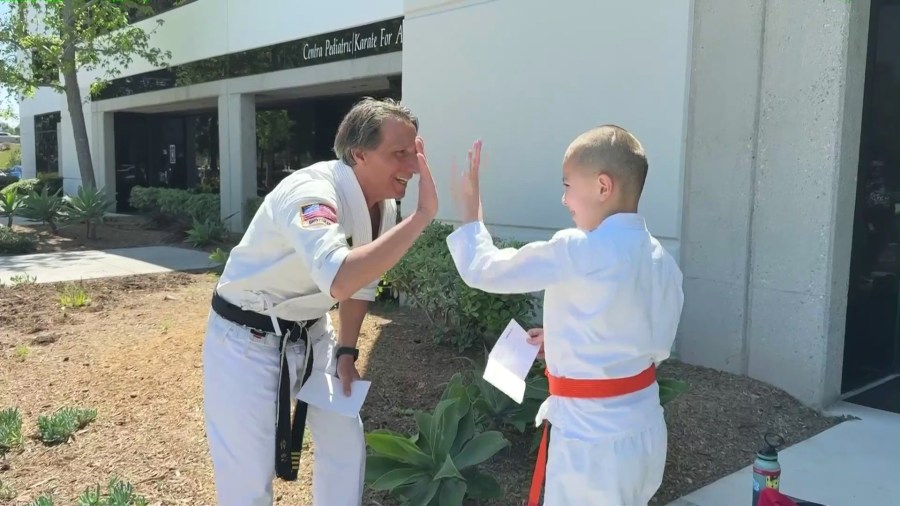 Sensei Wayne gives a high-five to a young student named Brendan who has autism. (KTLA)