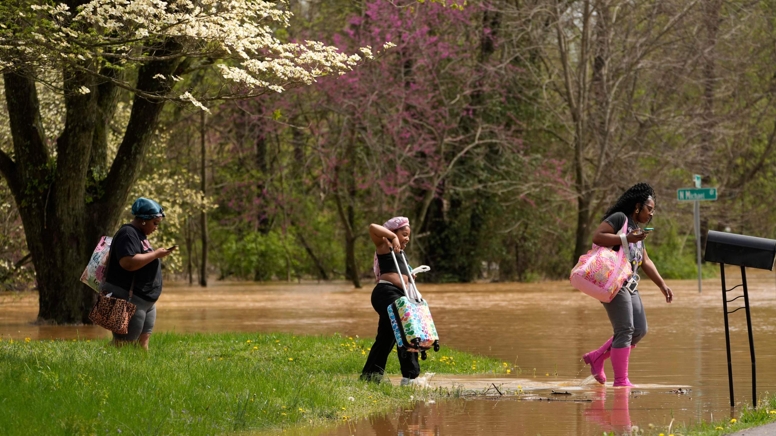 FILE - Marquetta Wheeler, right, with Samaria Williams and Jemaria Shaw, walk through flood waters as they leave their home on Marietta Drive in Hopkinsville, Ky., April 4, 2025. (AP Photo/George Walker IV, File)