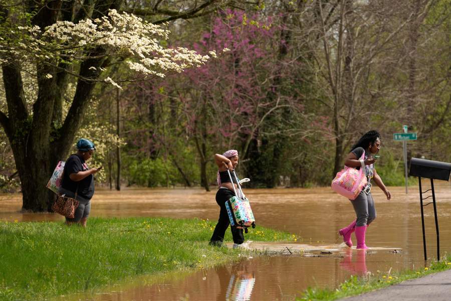 FILE - Marquetta Wheeler, right, with Samaria Williams and Jemaria Shaw, walk through flood waters as they leave their home on Marietta Drive in Hopkinsville, Ky., April 4, 2025. (AP Photo/George Walker IV, File)