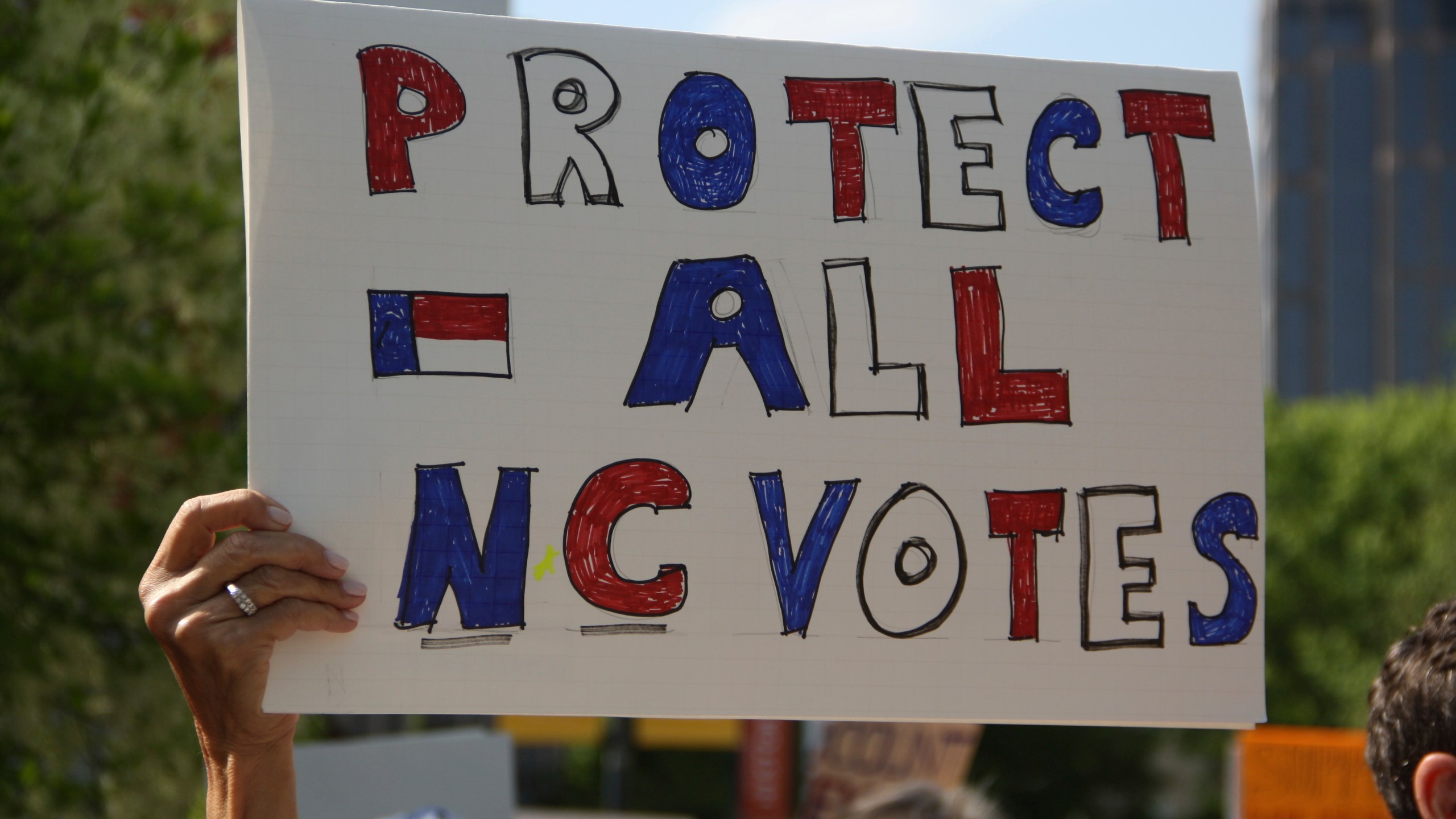 A protester listens to speeches during a rally for Democratic Associate Justice Allison Riggs in Raleigh, N.C., on Monday, April 14, 2025. (AP Photo/Makiya Seminera)