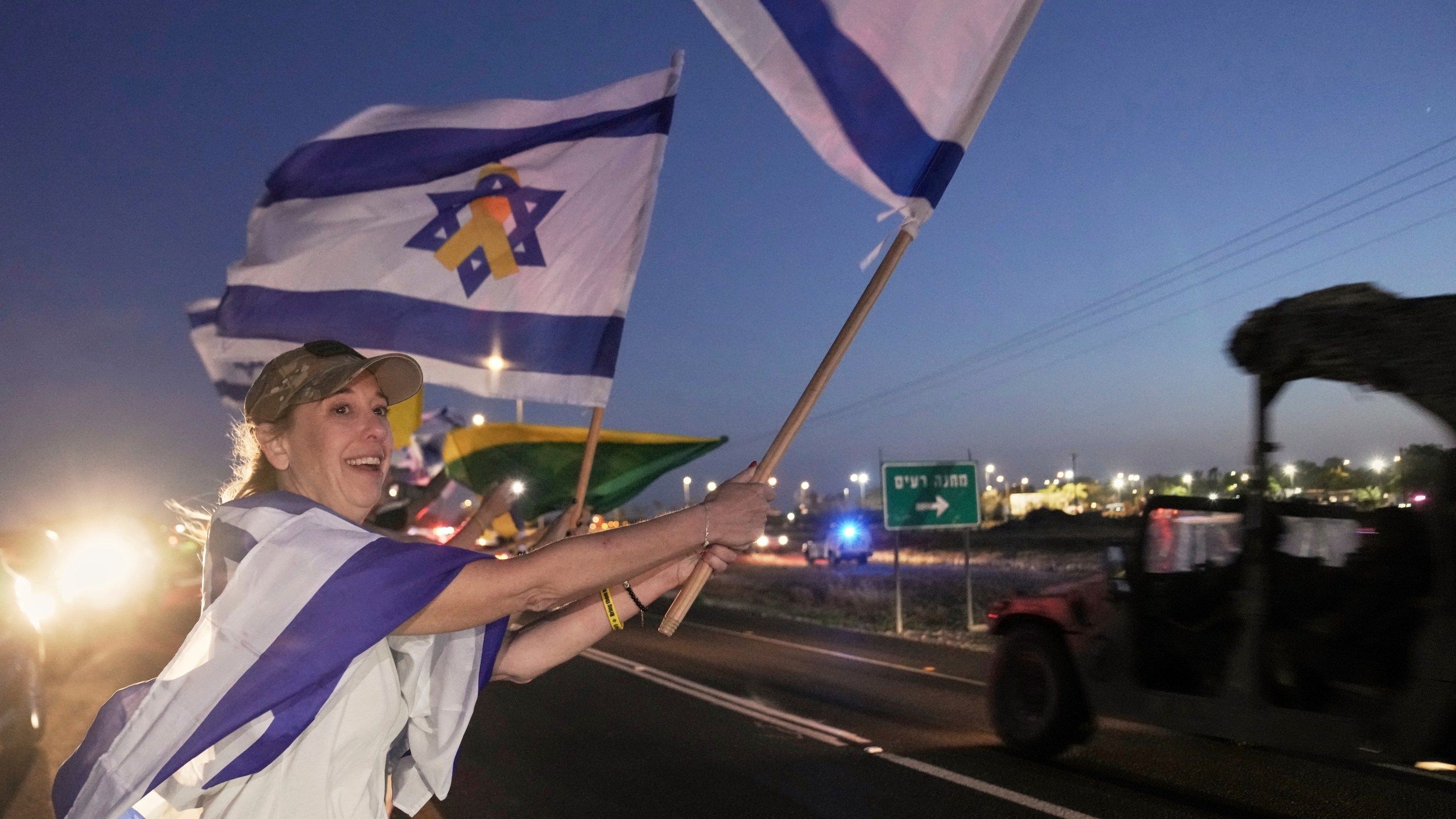 Amy Lieberman from Hillsdale, New Jersey, foreground, joins Israelis waving flags as the convoy carrying freed Israeli-American soldier Edan Alexander arrives after his release from Hamas captivity in Gaza to an army base in Reim, near the Gaza border, southern Israel, Monday, May 12, 2025.(AP Photo/Maya Alleruzzo)