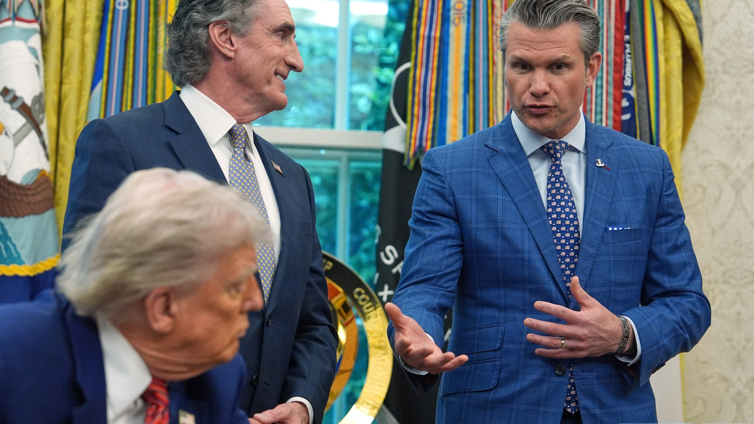 President Donald Trump and Interior Secretary Doug Burgum listen as Defense Secretary Pete Hegseth speaks before Trump signed executive orders regarding nuclear energy in the Oval Office of the White House, Friday, May 23, 2025, in Washington. (AP Photo/Evan Vucci)