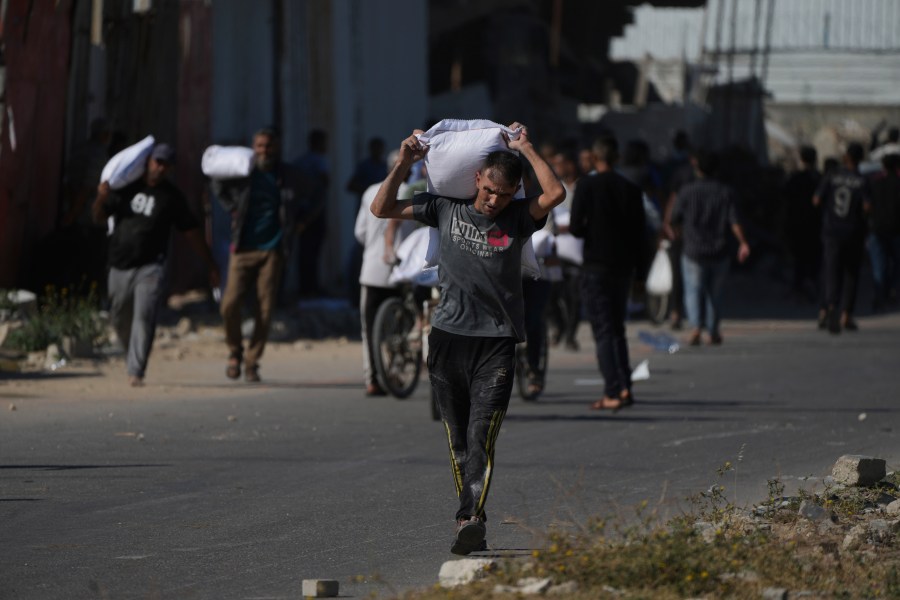 Palestinians carry bags of flour after storming a U.N. World Food Program warehouse in Zawaida, Central Gaza Strip, on Wednesday, May 28, 2025. (AP Photo/Abdel Kareem Hana)