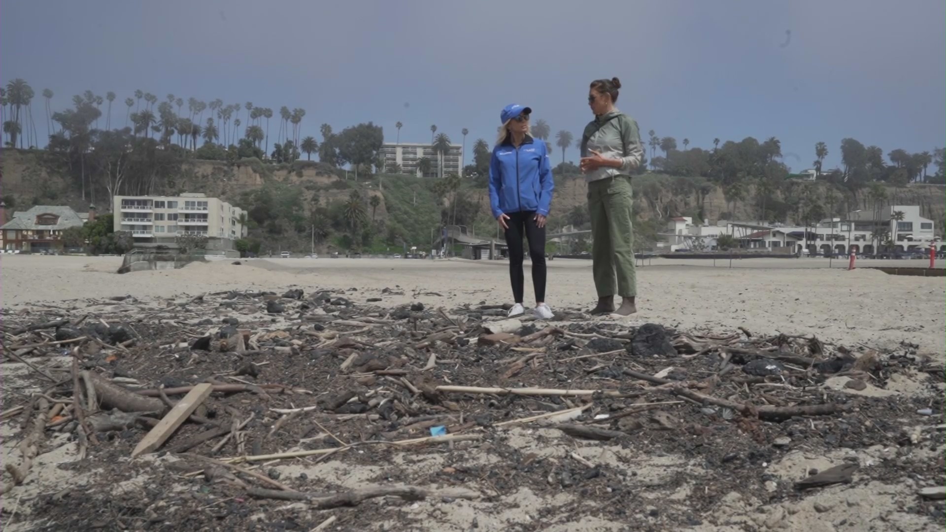 KTLA 5's Kacey Montoya stands next to conservation biologist Ashley Oleson in the Santa Monica Bay, observing some debris left behind from the Palisades Fire. (KTLA)