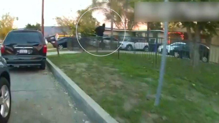 Rober Brown is seen climbing over a fence into a nearby home in San Bernardino as a police officer chases after him on Dec. 27, 2023. (San Bernardino Police Department)
