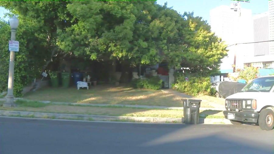 The problem property is seen obstructed by large trees, a notable amount of furniture, debris and several cars that appear inoperable. (KTLA)