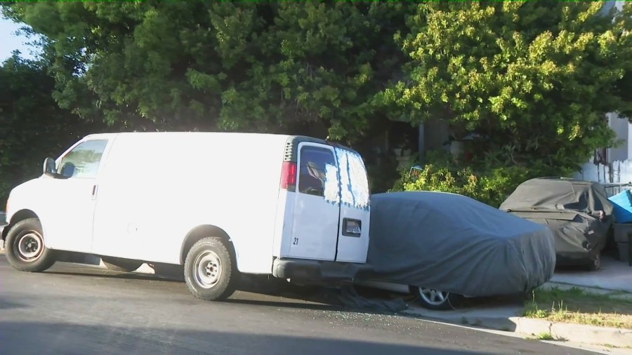 The problem property is seen obstructed by large trees, a notable amount of furniture, debris and several cars that appear inoperable. (KTLA)