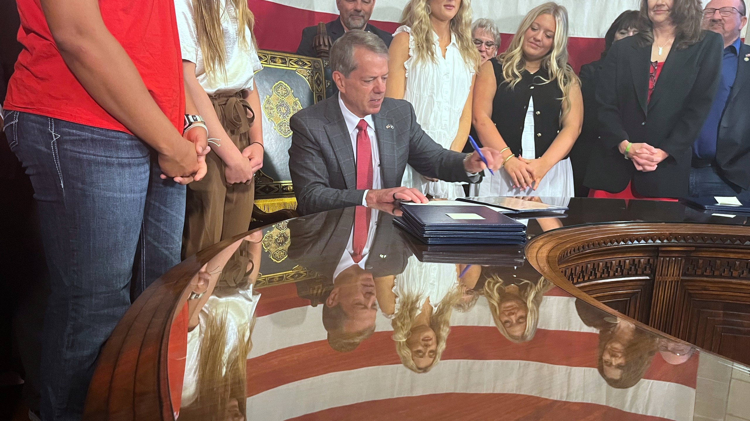 Nebraska Gov. Jim Pillen is flanked by supporters Wednesday, June 4, 2025 as he signs into law a bill banning transgender athletes from girls' sports. (AP Photo/Margery Beck)