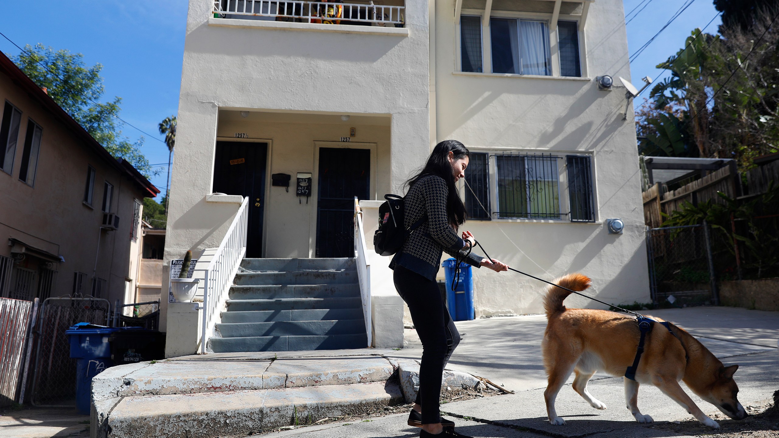 A woman walks her dog past apartment complexes on Vin Scully Avenue in Elysian Park, Los Angeles on March 27, 2023. (Getty Images)
