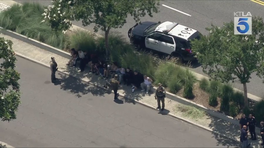 Aerial footage from Sky5 shows law enforcement officers detaining several people outside a Hacienda Heights home on June 27, 2025. (KTLA)