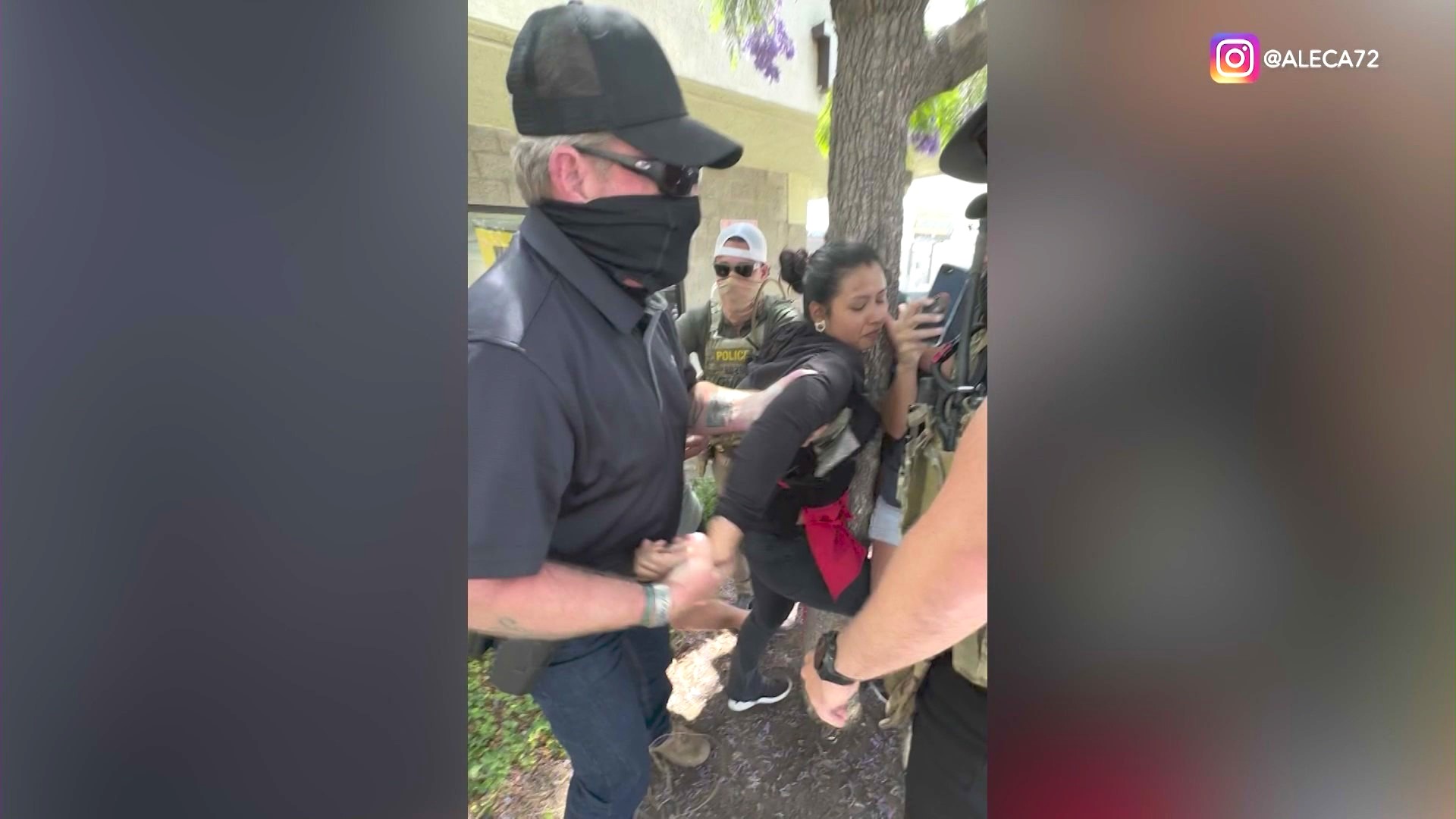 A street food vendor clings onto a tree before she was detained by immigration agents in Ladera Heights on June 23, 2025. Bystanders were yelling at the agents to identify themselves. (@aleca72)