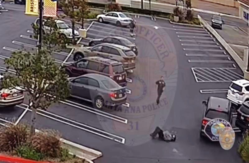 A security guard runs over to help the victim after he was run over by the fleeing suspects' car. (Santa Ana Police Department)
