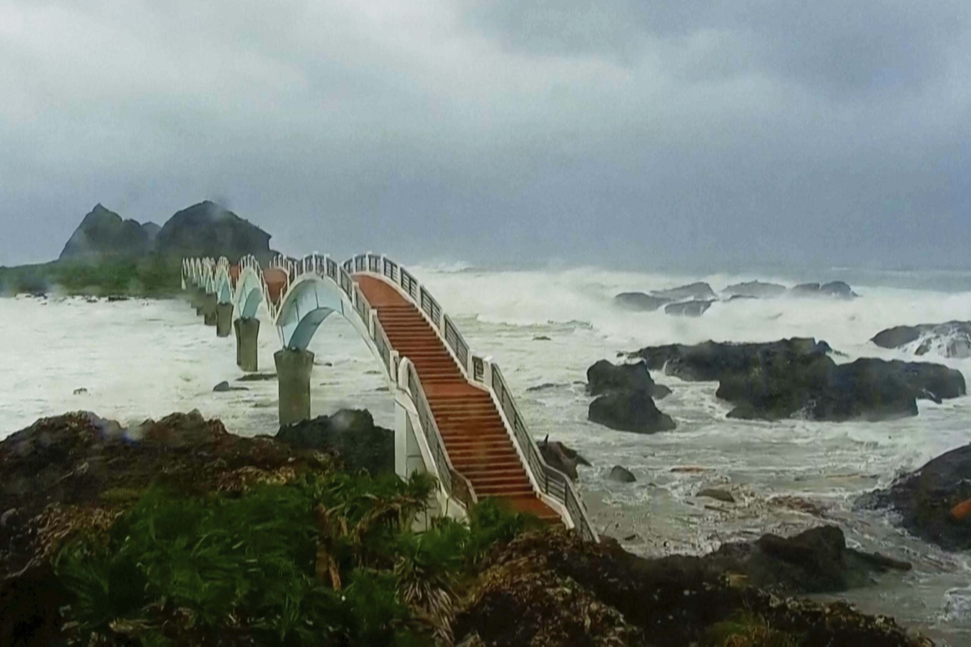 In this image made from video released by Taitung County Government, strong waves and heavy rain pound the Sansiiantai tourist spot on Aug. 13, 2025, as Typhoon Podul reaches Taitung, eastern Taiwan. (Taitung County Government via AP)