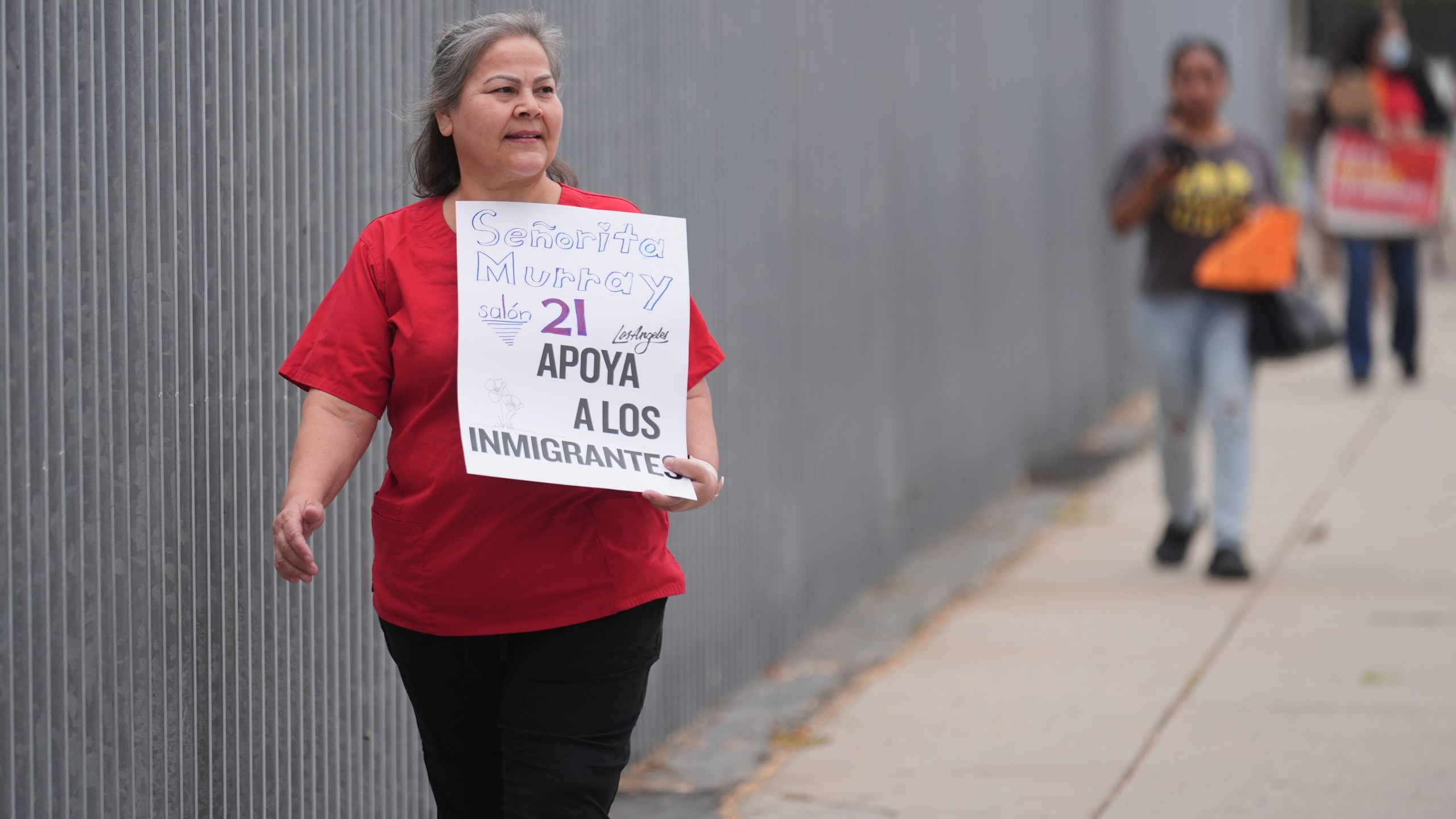 Teacher Martina Murray holds a sign supporting immigrants on the first day of school Thursday, Aug. 14, 2025, in Los Angeles. (AP Photo/Marcio Jose Sanchez)