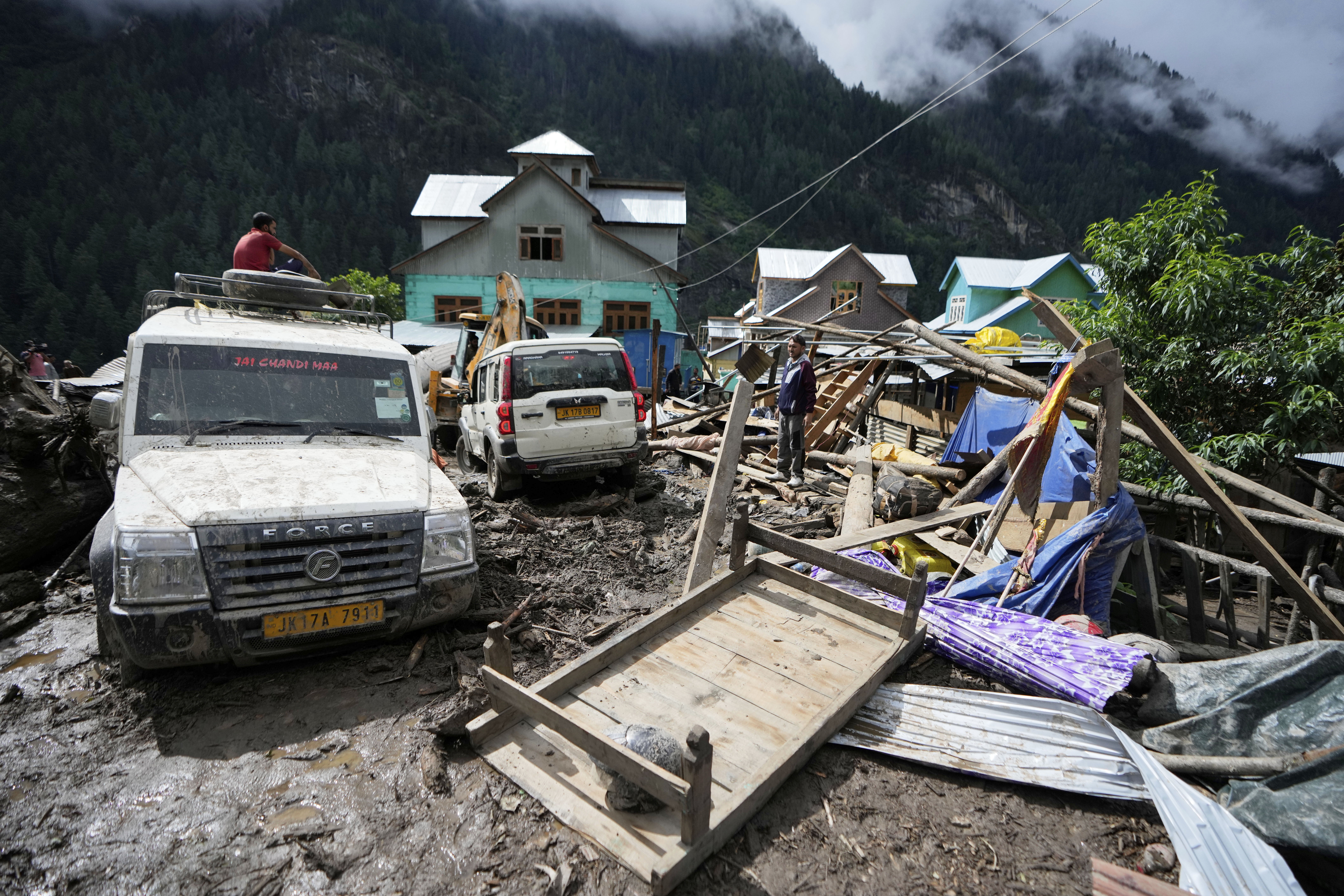 Household goods are strewn around next to buildings damaged by flash floods in Chositi village, Kishtwar district, Indian-controlled Kashmir, Friday, Aug. 15, 2025. (AP Photo/Channi Anand)