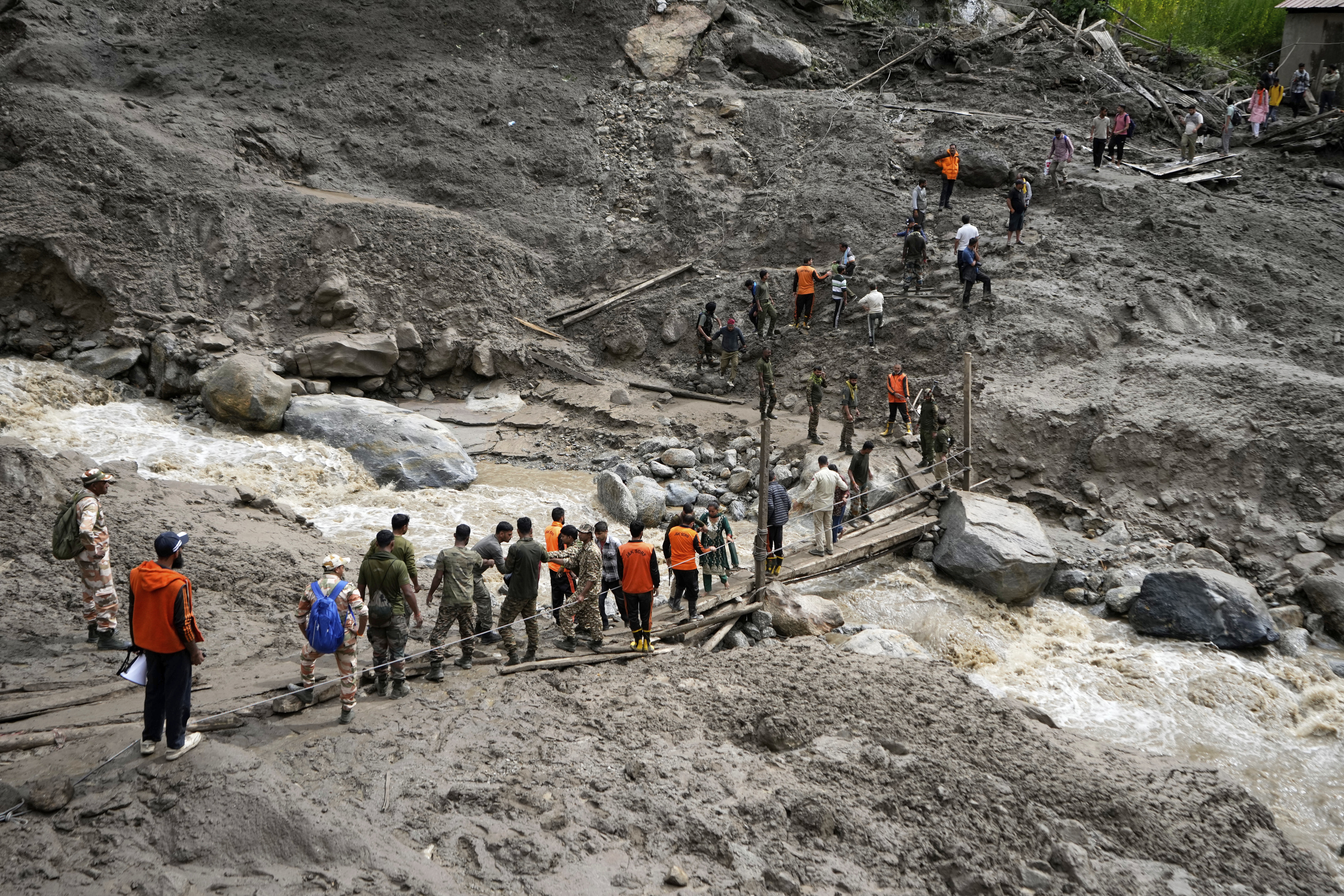 Stranded pilgrims are helped across a water channel using a makeshift bridge a day after flash floods in Chositi village, Kishtwar district, Indian-controlled Kashmir, Friday, Aug. 15, 2025. (AP Photo/Channi Anand)