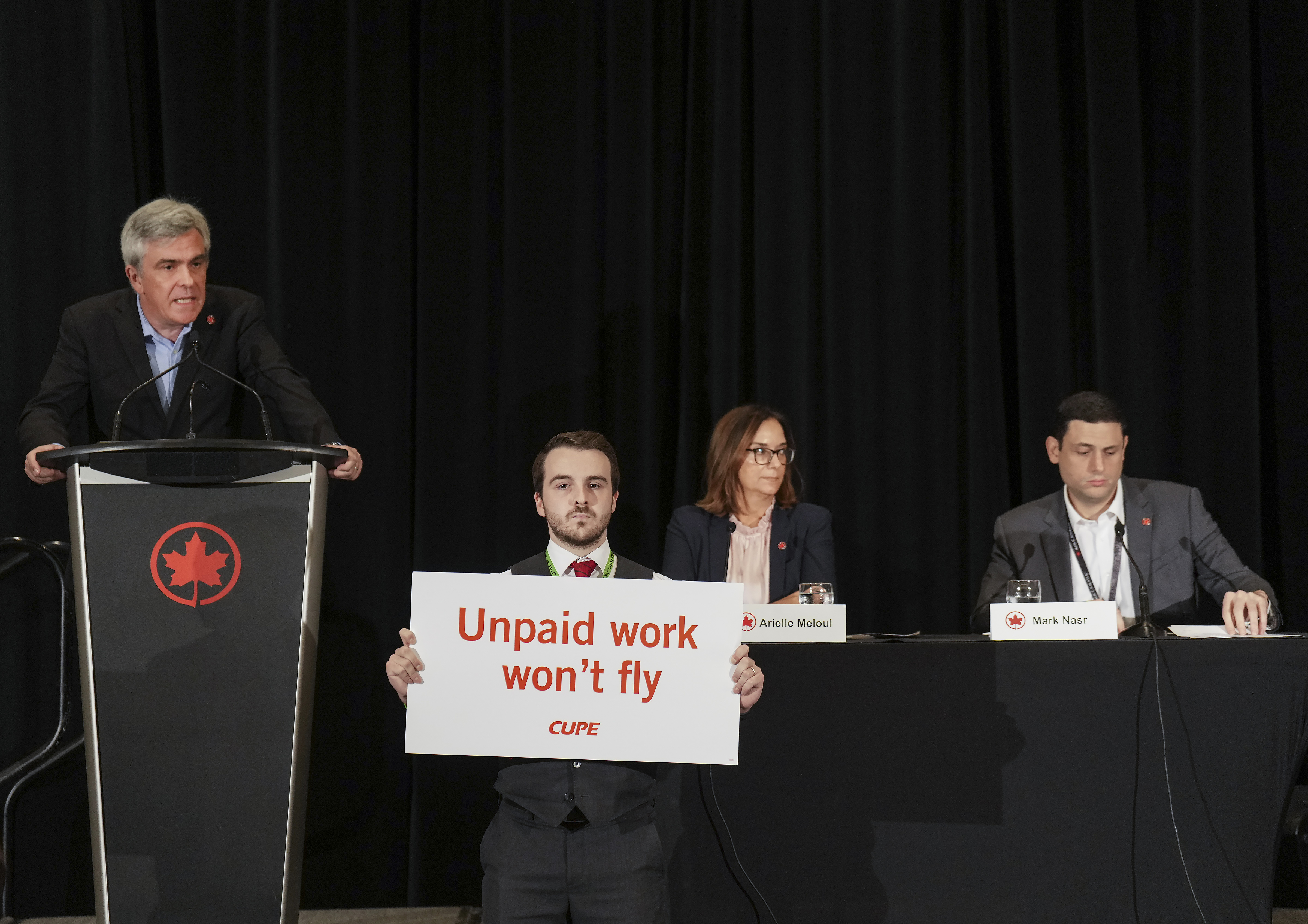 Air Canada executives are interrupted by Air Canada flight attendants during a press conference as a possible strike looms, in Toronto, on Thursday, Aug. 14, 2025. (Nathan Denette/The Canadian Press via AP)