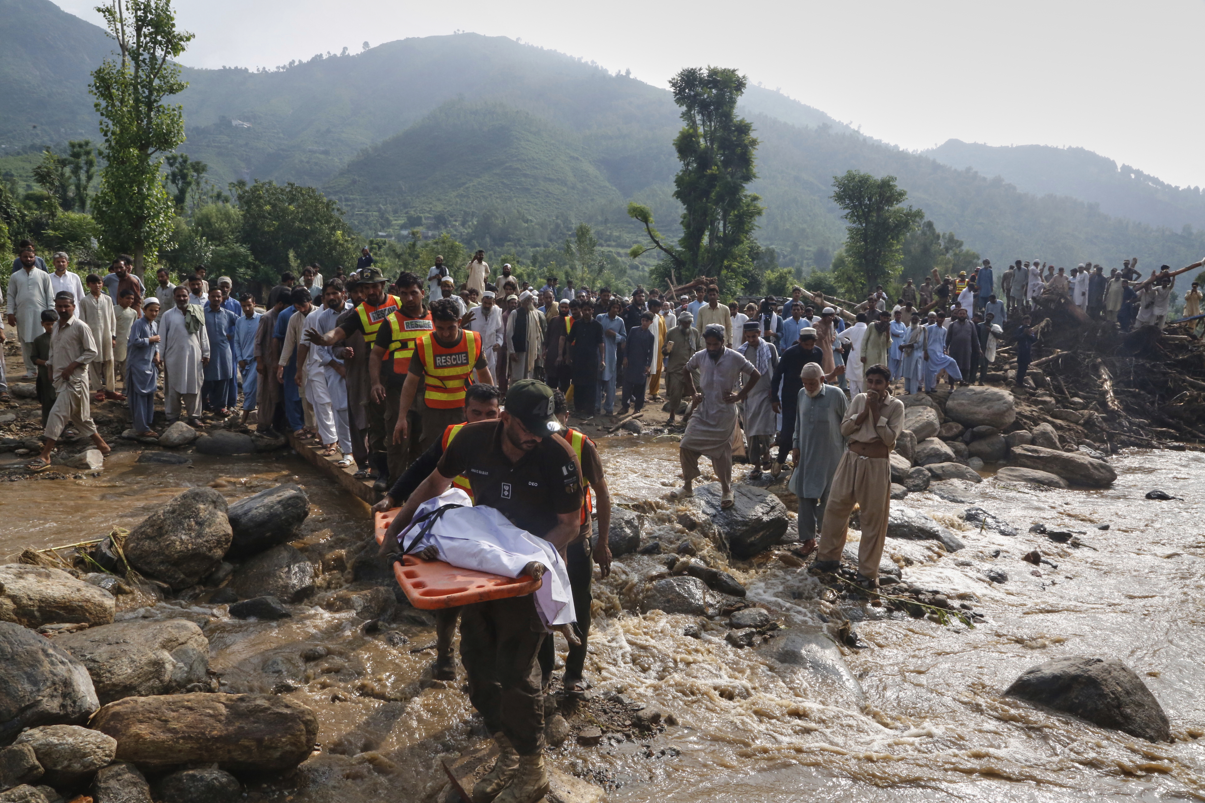 Rescue workers transport the body a victim of Friday's flash flooding after recovering it from the rubble of a damaged house at Qadir Nagar village near Pir Baba, Buner district, in Pakistan's northwest, Saturday, Aug. 16, 2025. (AP Photo/Muhammad Sajjad)