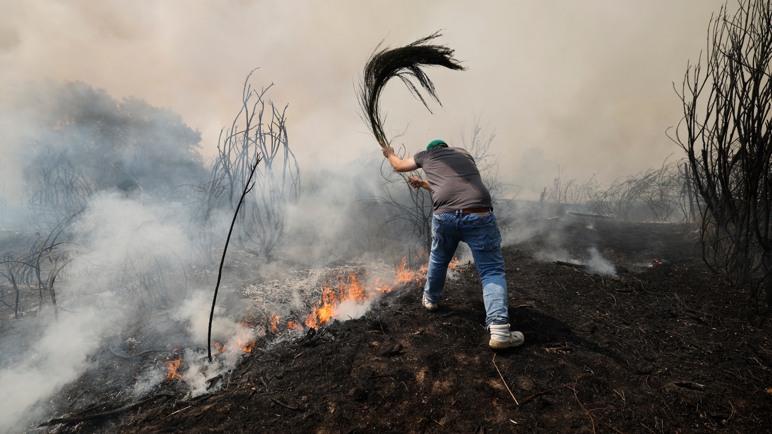 A man battles a wildfire in Veiga das Meas, northwestern Spain, Saturday, Aug. 16, 2025. (AP Photo/Lalo R. Villar)