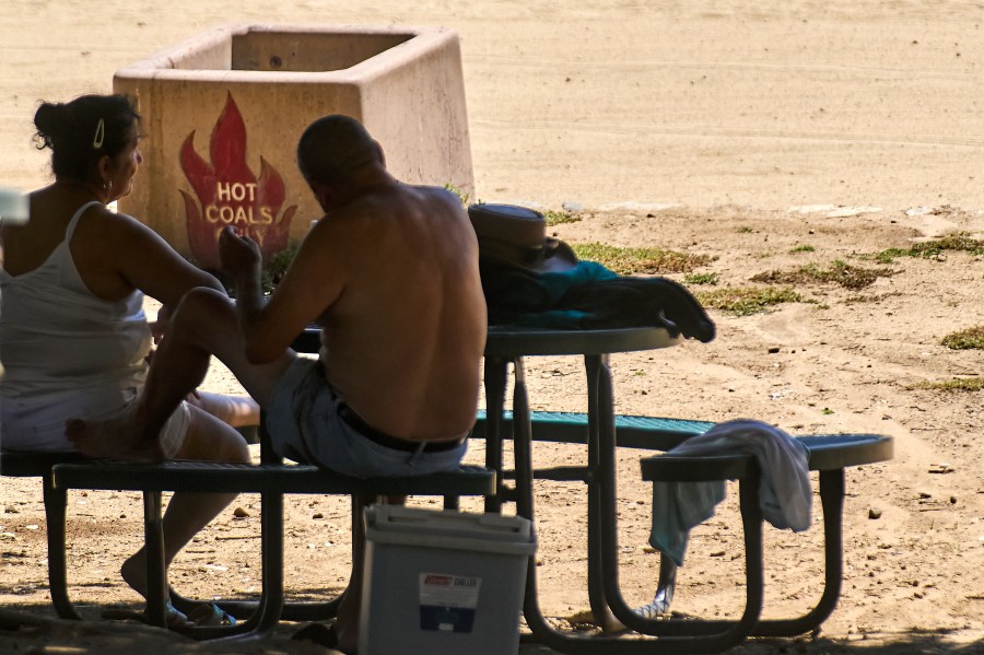 A couple sits in the shade as temperatures rise Wednesday, Aug. 20, 2025, at Castaic Lake in Los Angeles County, Calif. (AP Photo/Damian Dovarganes)