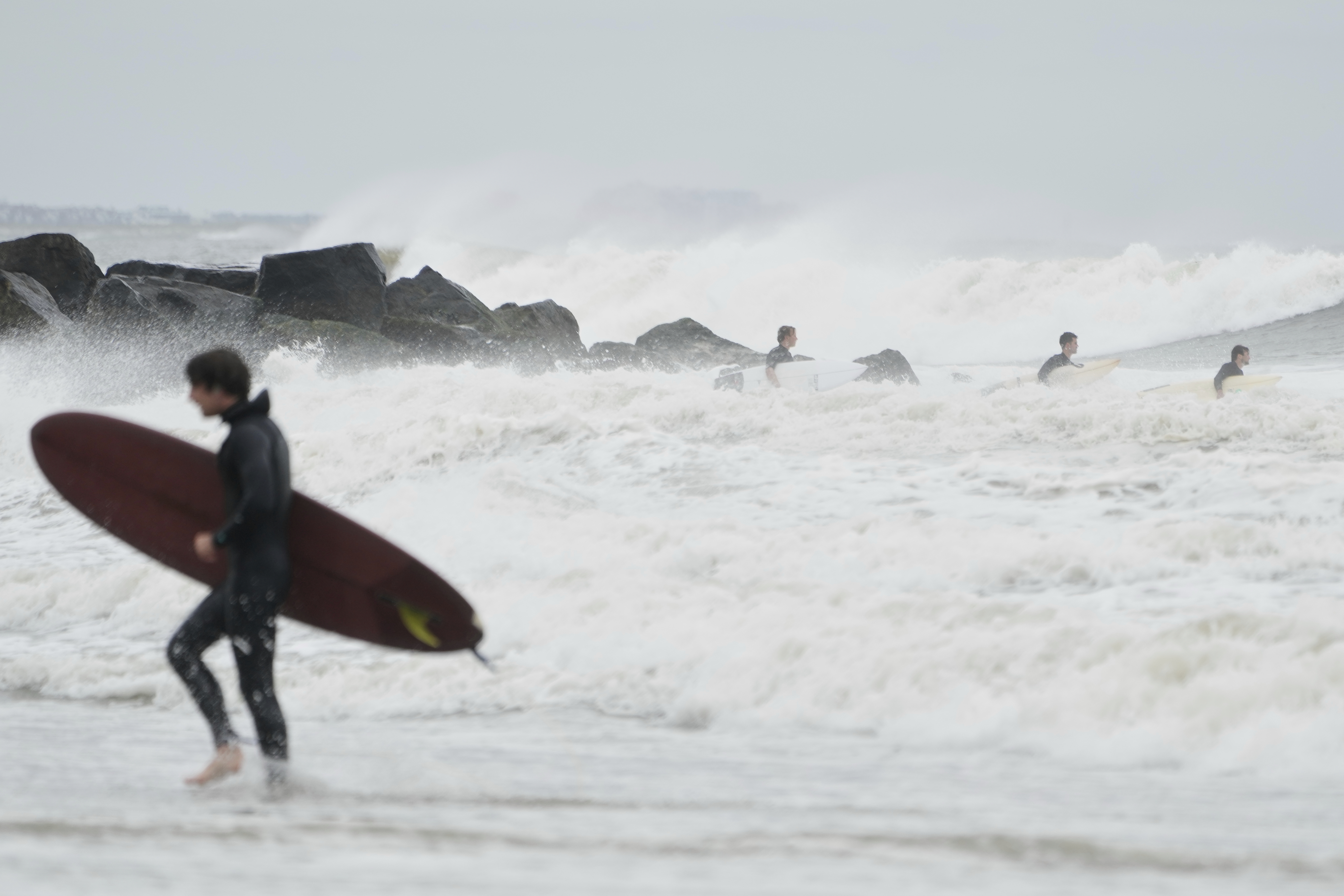 Surfers try to get in the water, past big waves bolstered by Hurricane Erin, at Rockaway Beach in the Queens borough of New York, Thursday, Aug. 21, 2025. (AP Photo/Seth Wenig)