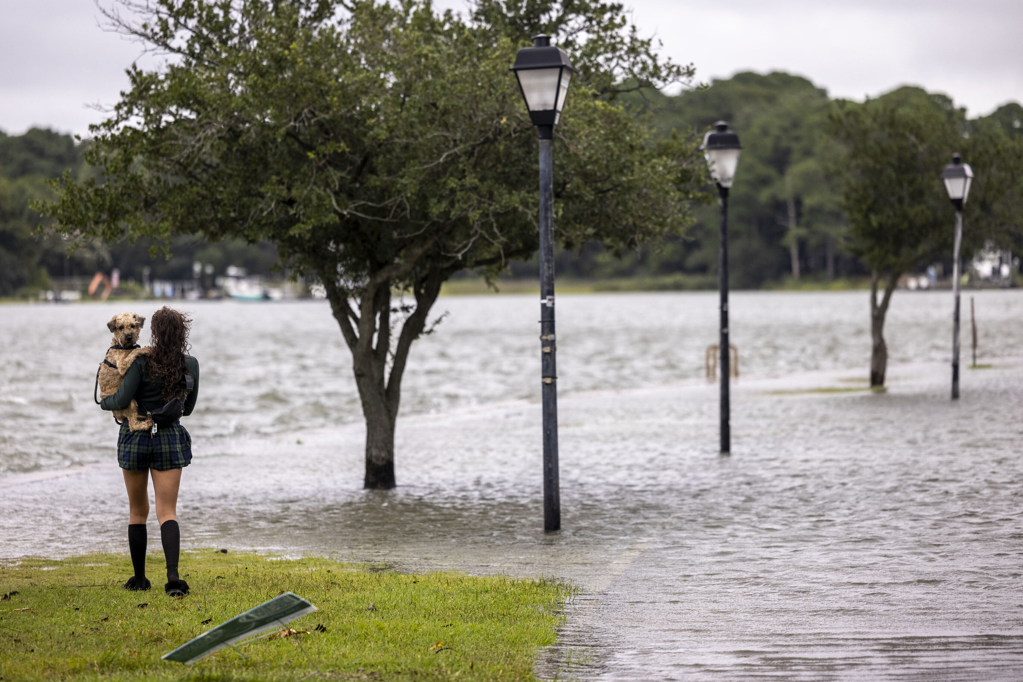 Brianna Quick holds her dog Hina while checking out the coastal flooding in the Colonial Place neighborhood of Norfolk, Va., as a result of Hurricane Erin, Thursday, Aug. 21, 2025. (Kendall Warner/The Virginian-Pilot via AP)