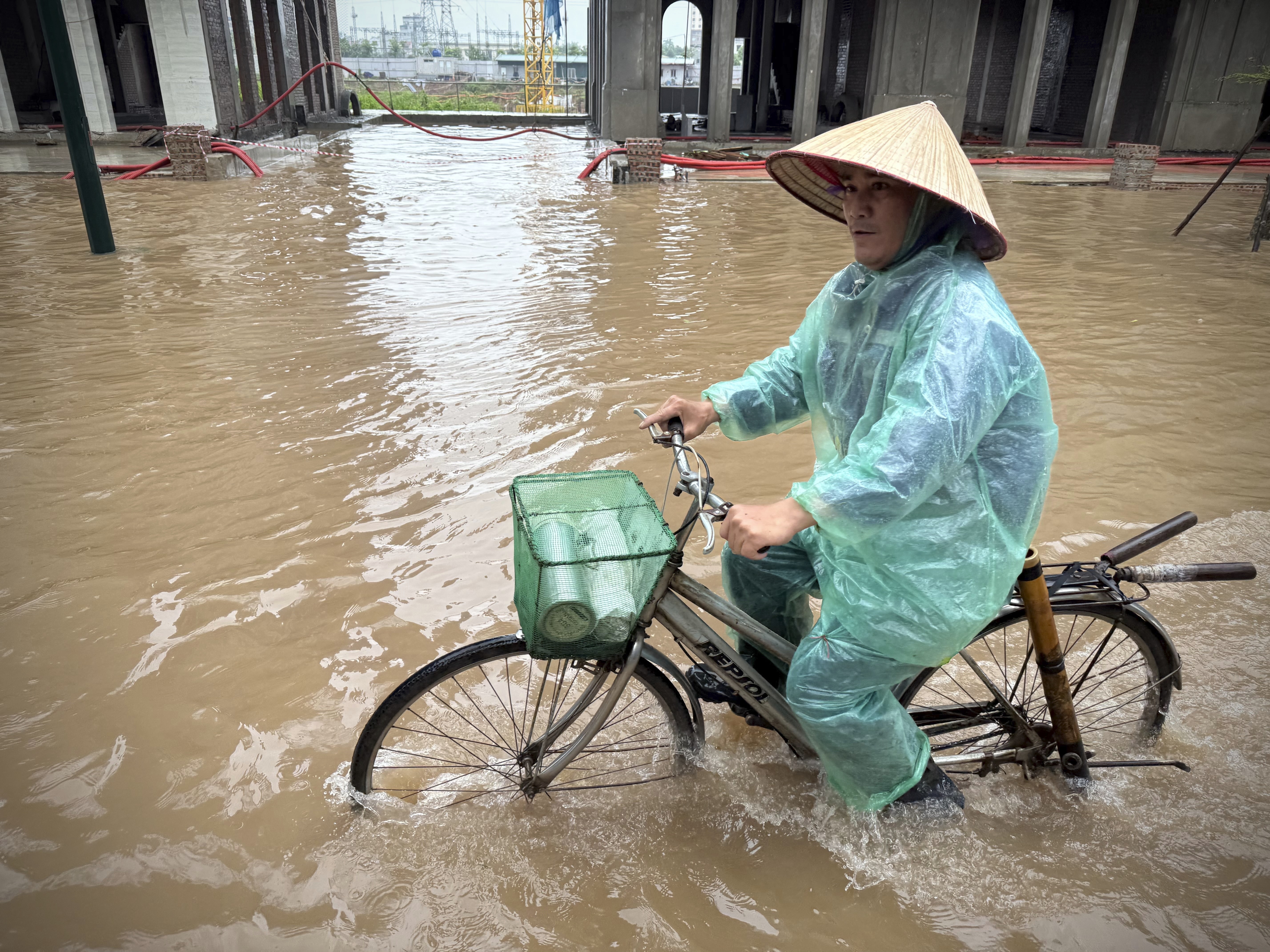 A man rides a bicycle on a flooded street caused by Typhoon Kajiki in Hanoi, Vietnam, Wednesday, Aug. 27, 2025. (AP Photo/Hau Dinh)