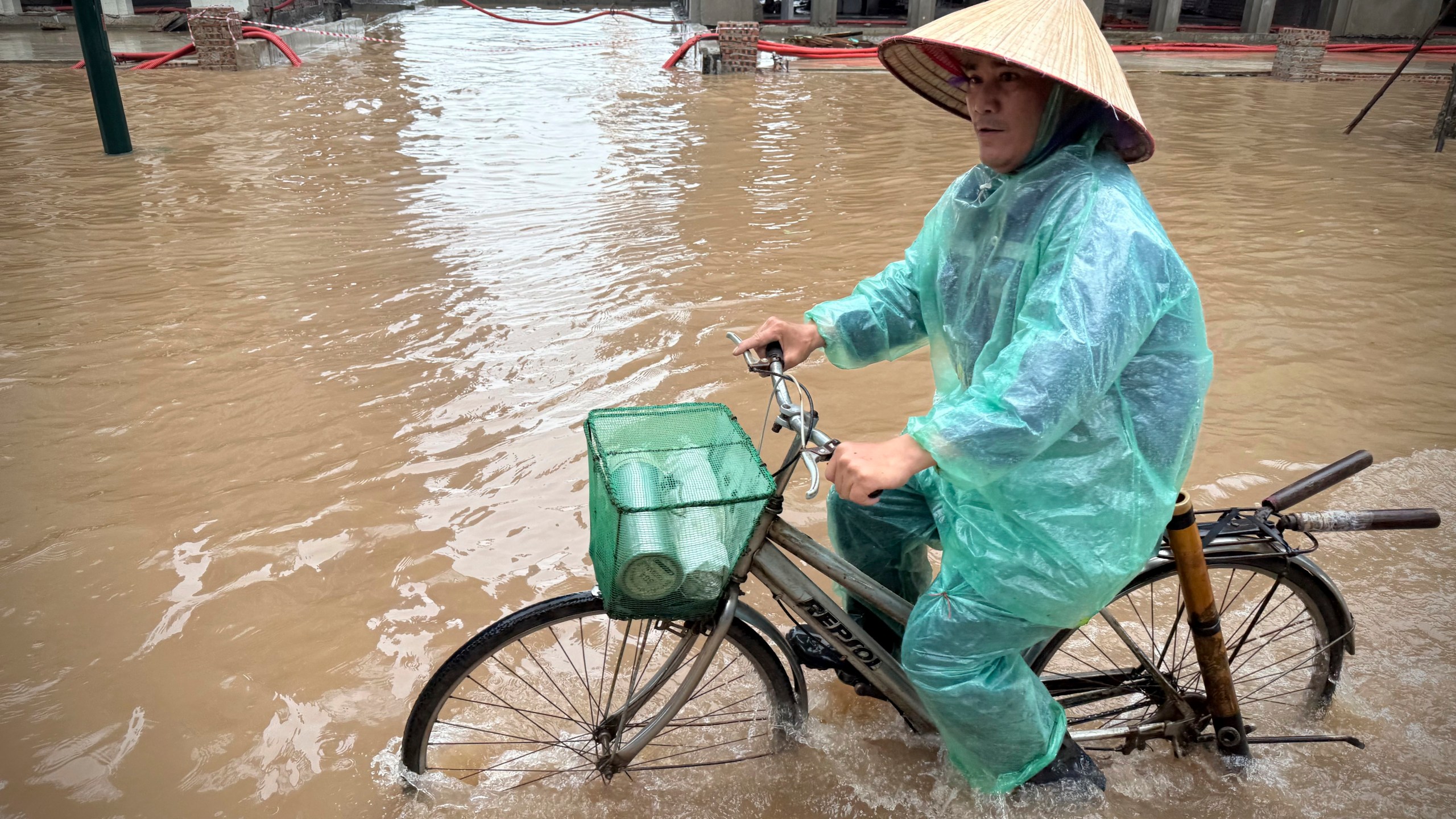 A man rides a bicycle on a flooded street caused by Typhoon Kajiki in Hanoi, Vietnam, Wednesday, Aug. 27, 2025. (AP Photo/Hau Dinh)
