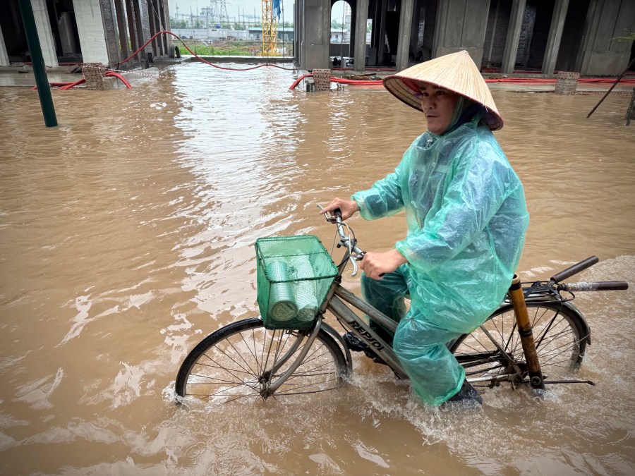 A man rides a bicycle on a flooded street caused by Typhoon Kajiki in Hanoi, Vietnam, Wednesday, Aug. 27, 2025. (AP Photo/Hau Dinh)