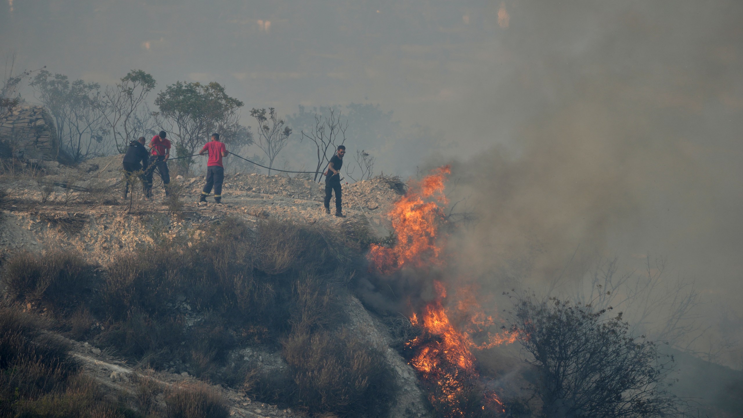 FILE - Residents try to extinguish a blaze in Omodos village, Cyprus, during a wildfire on the southern side of the east Mediterranean island nation's Troodos mountain range, July 24, 2025. (AP Photo/Petros Karadjias, File)