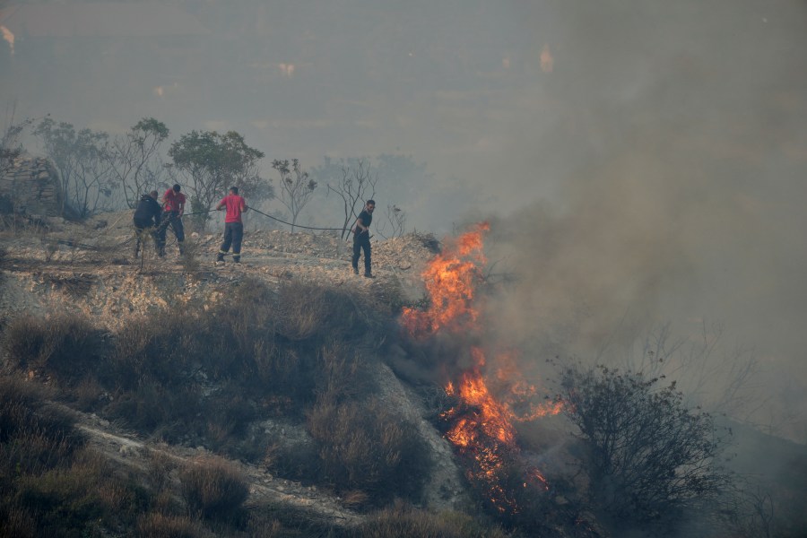 FILE - Residents try to extinguish a blaze in Omodos village, Cyprus, during a wildfire on the southern side of the east Mediterranean island nation's Troodos mountain range, July 24, 2025. (AP Photo/Petros Karadjias, File)