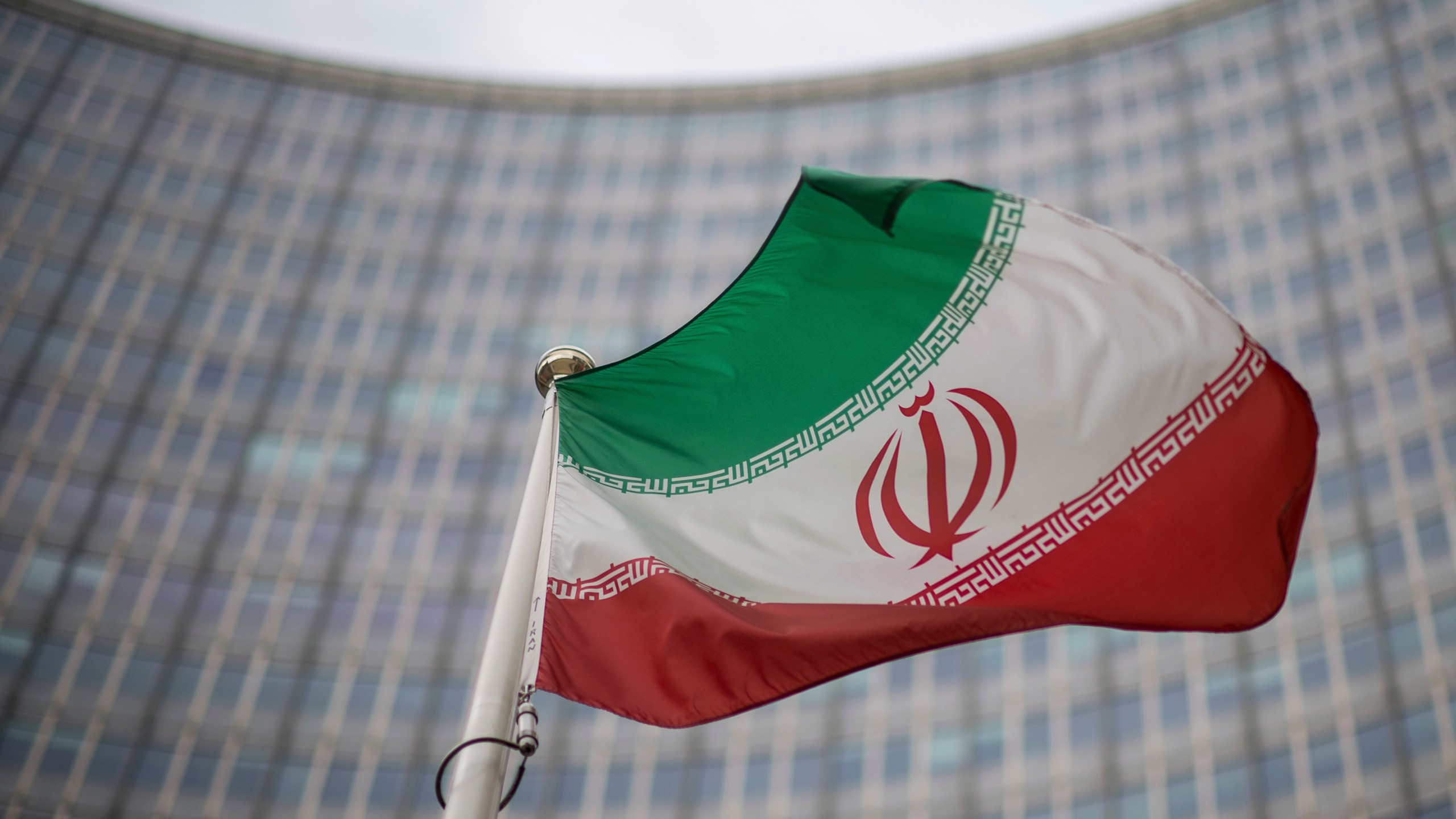File - A national flag of Iran waves in front of the building of the International Atomic Energy Agency, IAEA, in Vienna, Austria, Friday, Dec. 17, 2021. (AP Photo/Michael Gruber, File)