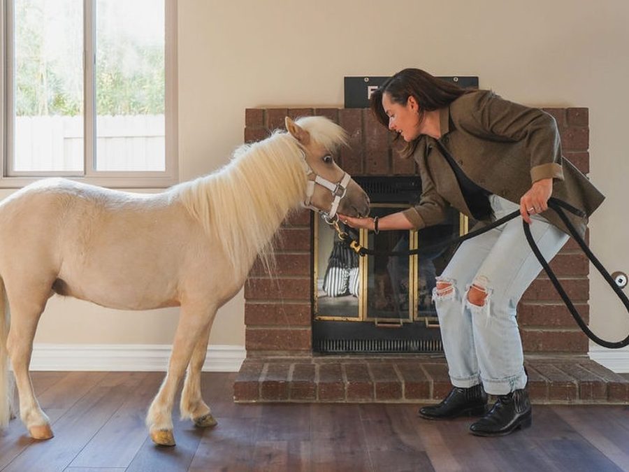 Lucy Oliveira and Lemon pose inside an empty living room shown in a viral real estate listing from August 2025. (Lauren Purves)