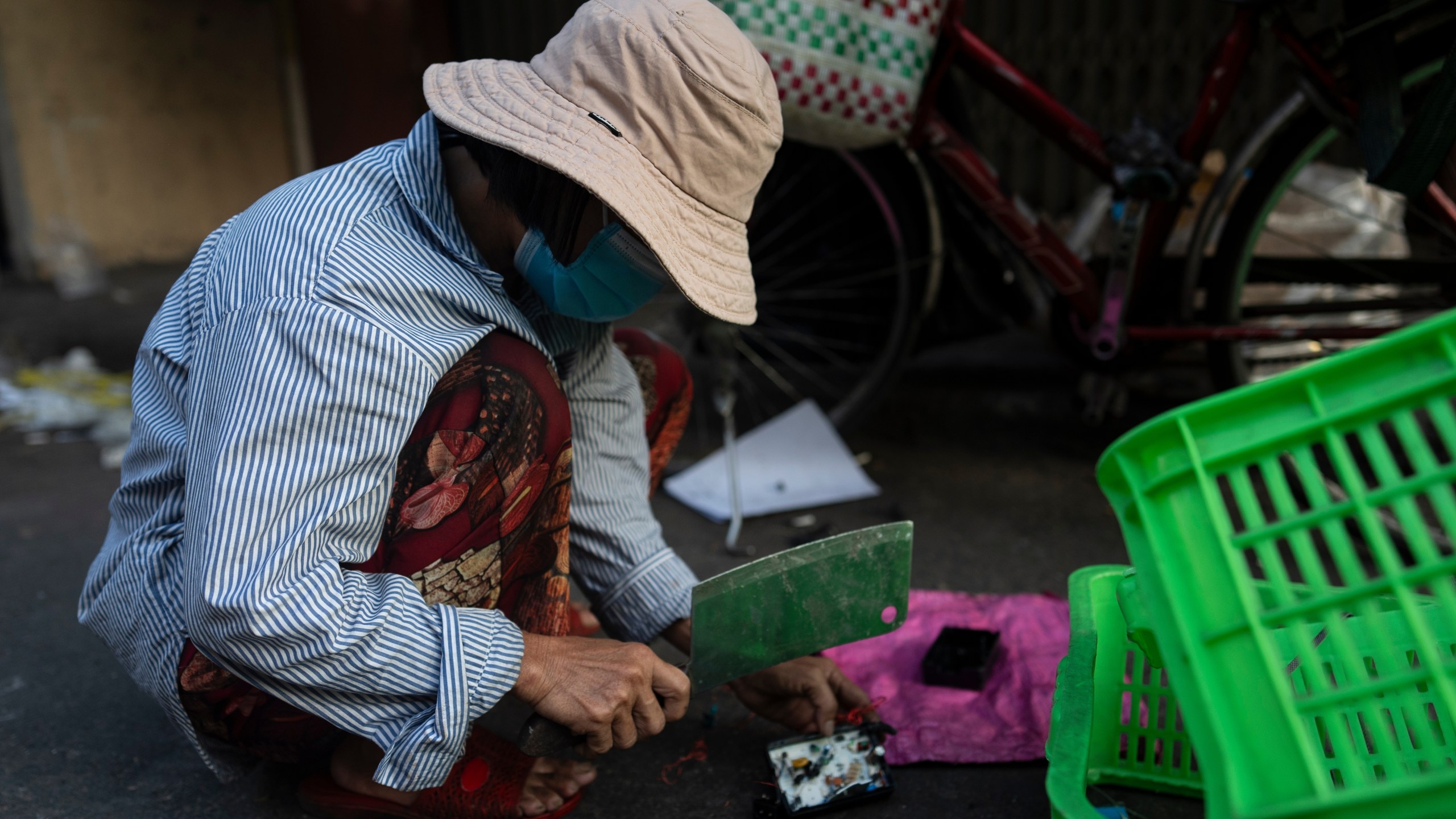 FILE - An e -waste collector uses a cleaver to remove copper wire from a device in Nhat Tao market, the largest informal recycling market in Ho Chi Minh City, Vietnam, Jan. 31, 2024. (AP Photo/Jae C. Hong, File)