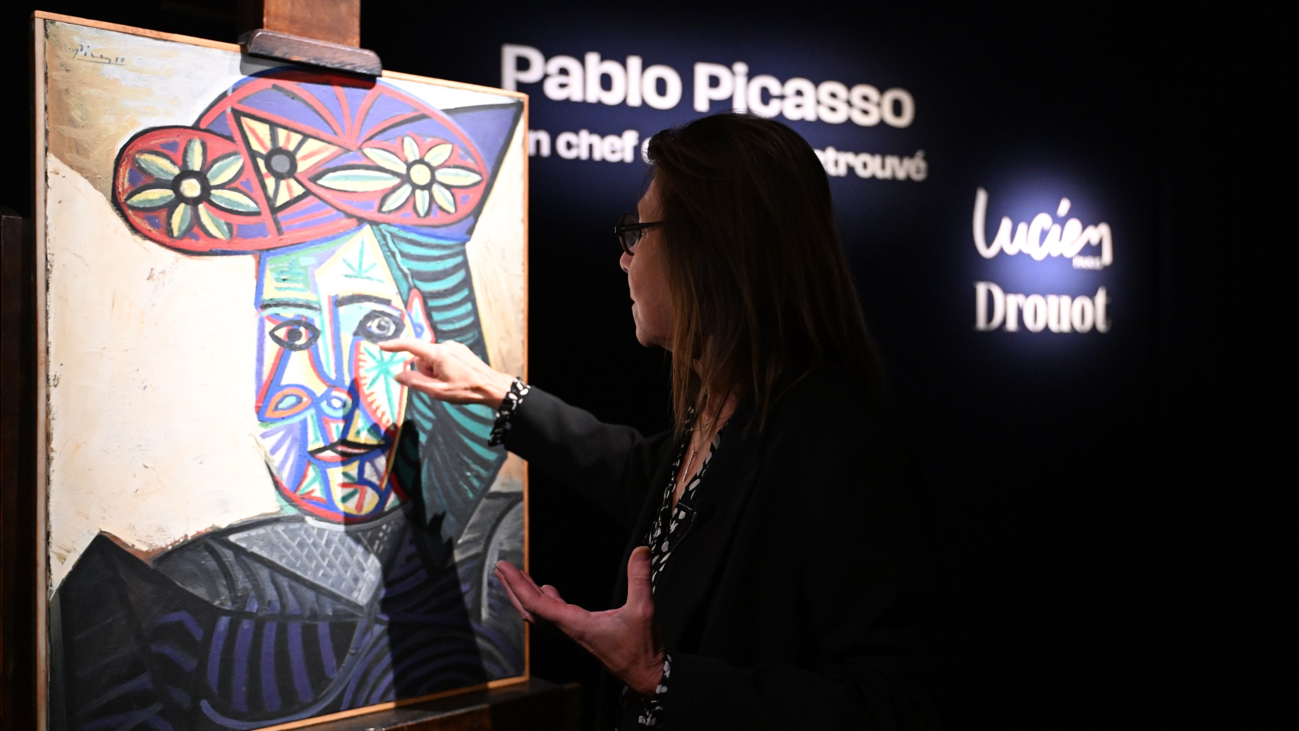 Art expert Agnes Sevestre-Barbe points to a rediscovered Picasso painting "Bust of a Woman in a Flowery Hat", Wednesday, Oct. 22, 2025 in Paris. The portrait painted in 1943 will be sold at auction Friday in Paris, was bought in 1944 and shows his partner Dora Maar. (AP Photo/Emma Da Silva)