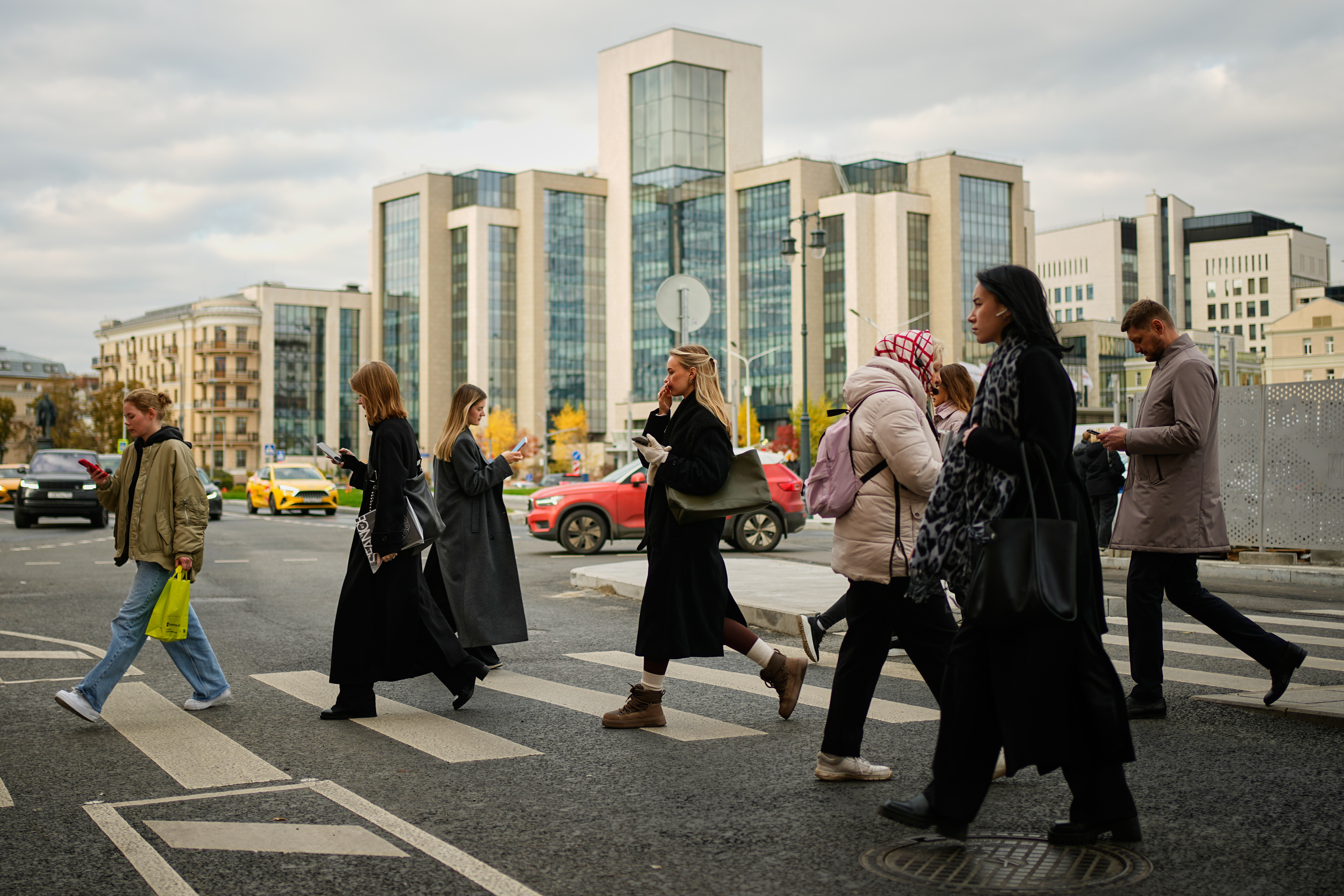 People cross a street, with Russian oil company Lukoil's headquarters seen in the background, in Moscow, Russia, Thursday, Oct. 23, 2025. (AP Photo/Pavel Bednyakov)