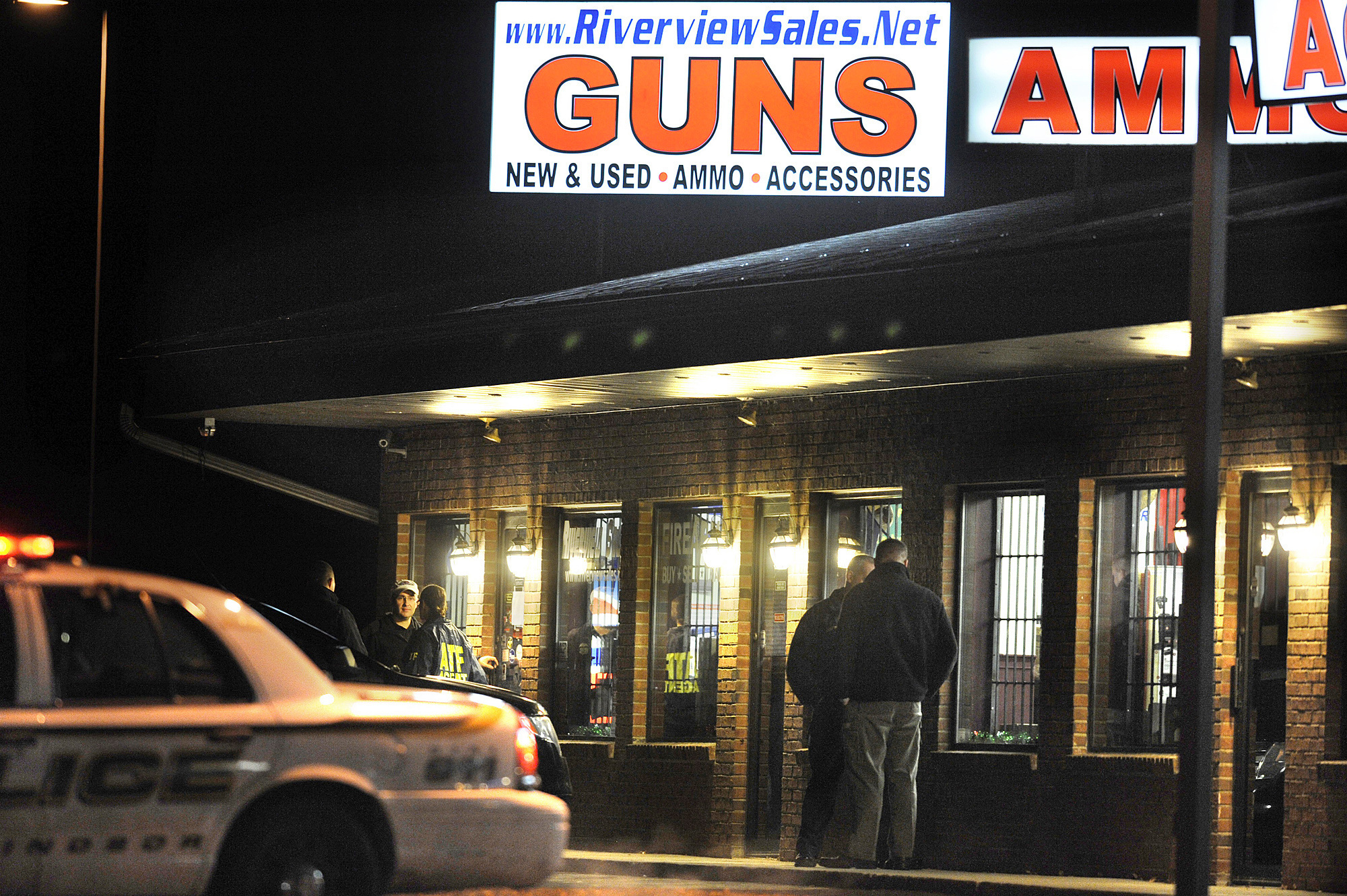 FILE - In this Dec. 20, 2012 file photo, law enforcement officials stand outside Riverview Gun Sales, as authorities raid the store in East Windsor, Conn. (AP Photo/Jessica Hill, File)