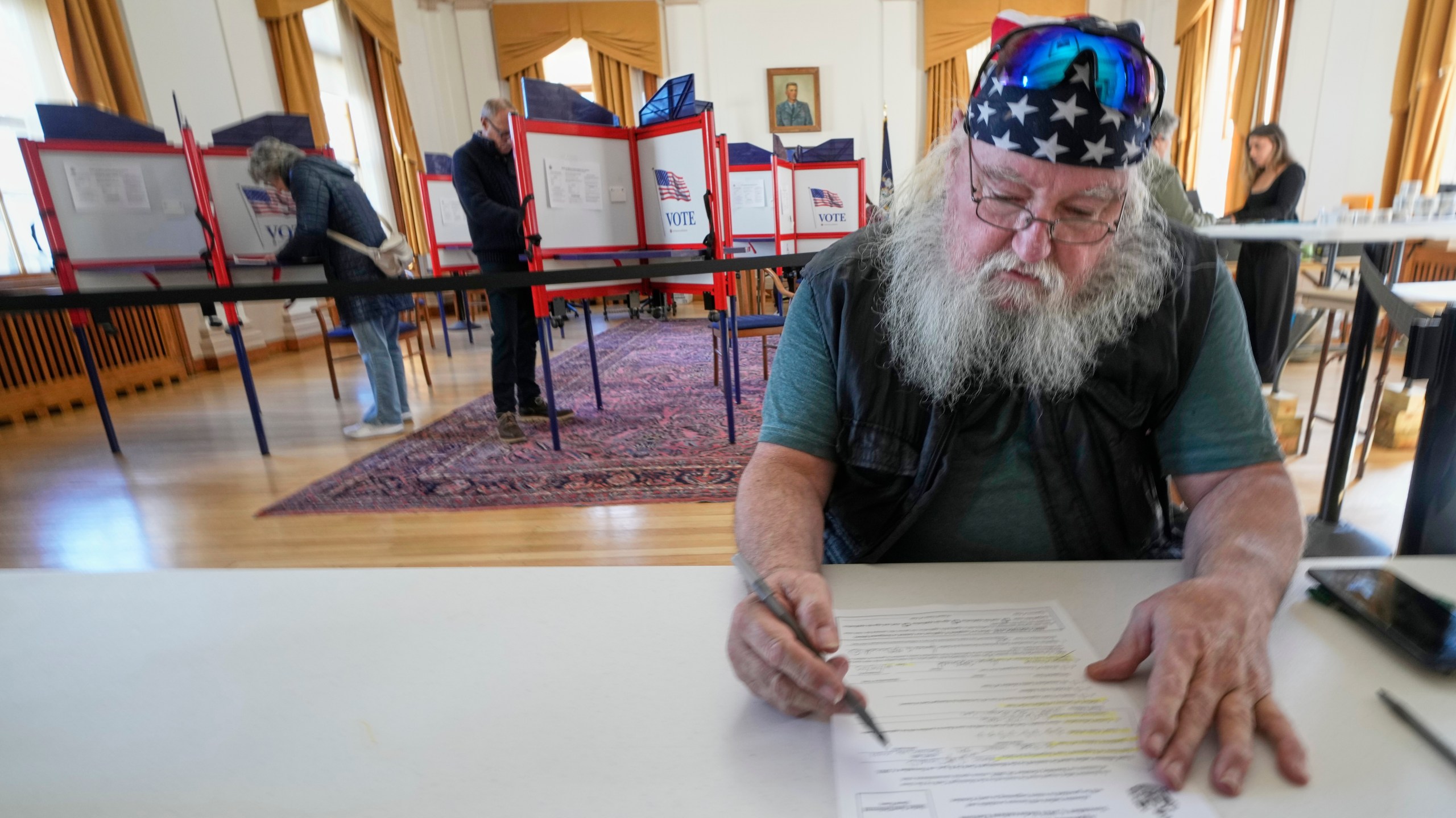 Jim McDonald fills out a form for early voting, Tuesday, Oct. 28, 2025, in Portland, Maine. (AP Photo/Robert F. Bukaty)