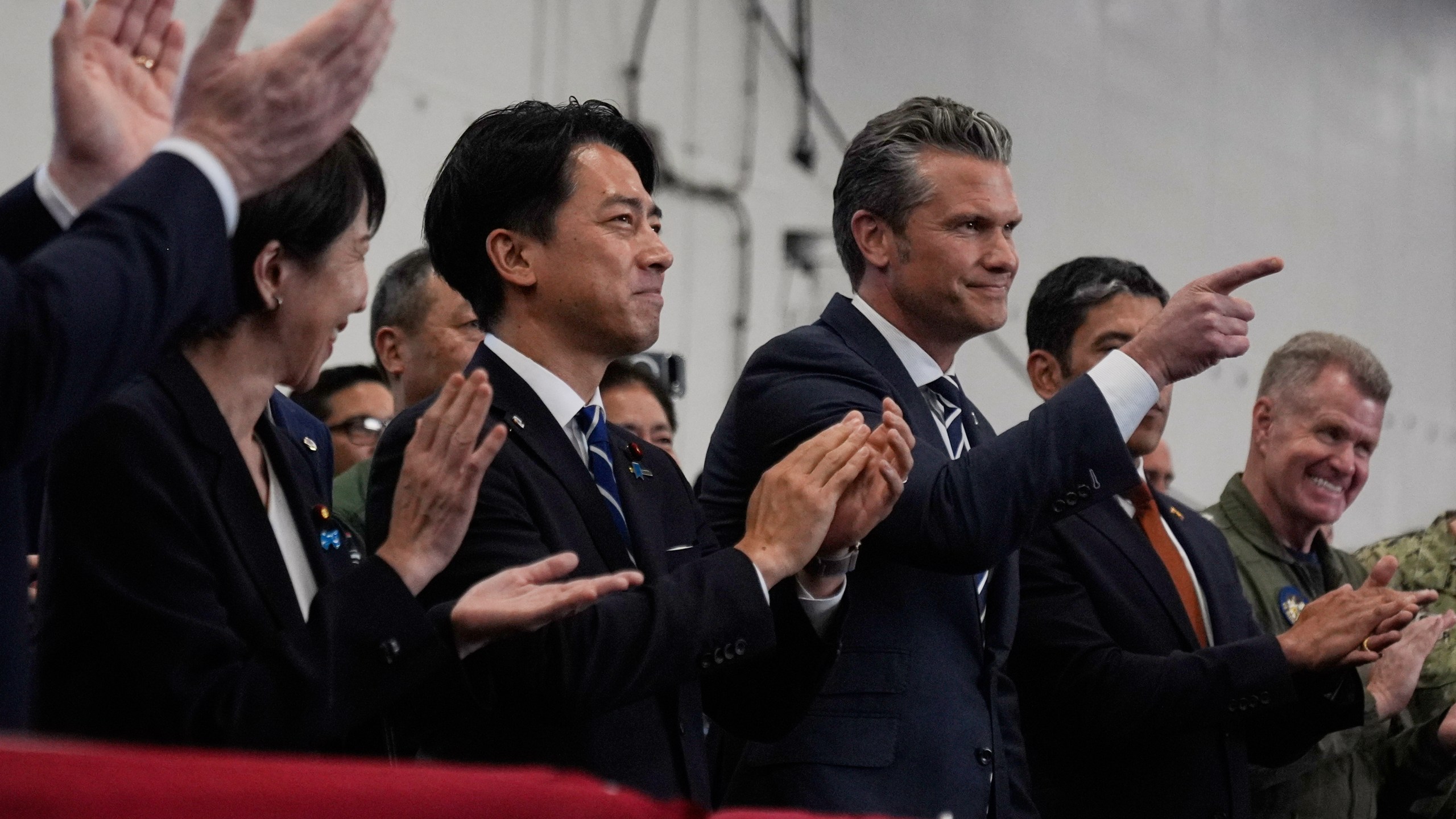 U.S. Defense Secretary Pete Hegseth, center right, with Japanese Prime Minister Sanae Takaichi, left, and Defense Minister Shinjiro Koizumi, gestures as they listen to President Donald Trump speak to members of the military aboard the USS George Washington, an aircraft carrier docked at an American naval base, in Yokosuka, south of Tokyo, Tuesday, Oct. 28, 2025. (AP Photo/Mark Schiefelbein)
