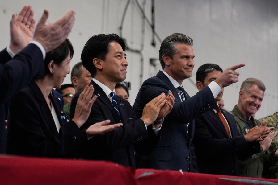 U.S. Defense Secretary Pete Hegseth, center right, with Japanese Prime Minister Sanae Takaichi, left, and Defense Minister Shinjiro Koizumi, gestures as they listen to President Donald Trump speak to members of the military aboard the USS George Washington, an aircraft carrier docked at an American naval base, in Yokosuka, south of Tokyo, Tuesday, Oct. 28, 2025. (AP Photo/Mark Schiefelbein)
