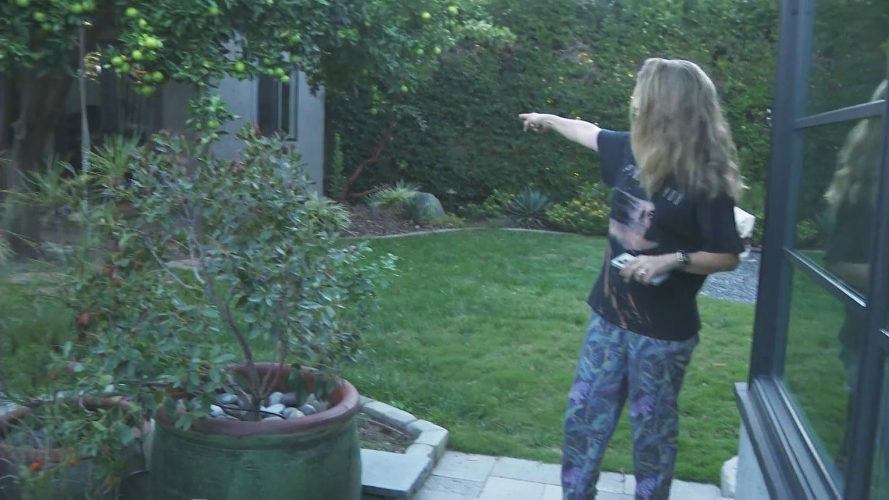 Lea Young pointing out the location of her husband's detached office in their backyard. (KTLA)